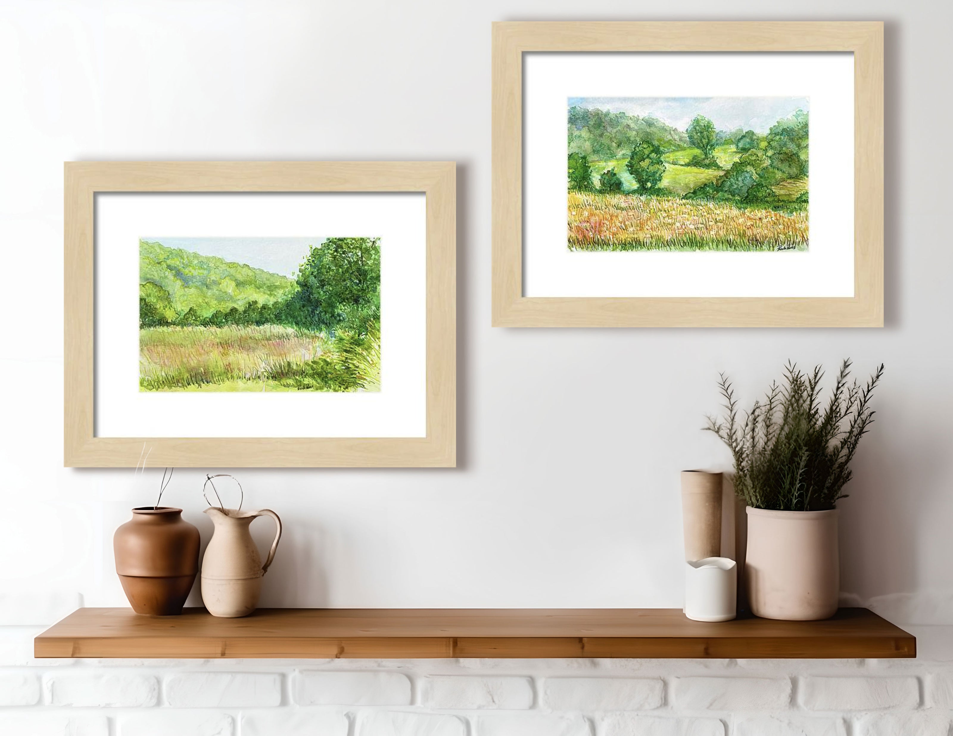 Two watercolors of the countryside on a wall above a shelf