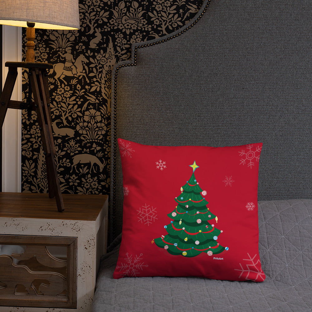 Christmas tree pillow with a red background on a bed. It looks comfy and cozy.