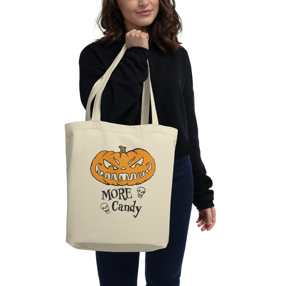 Woman holding the canvas tote bag with the more candy hungry pumpkin design on the front
